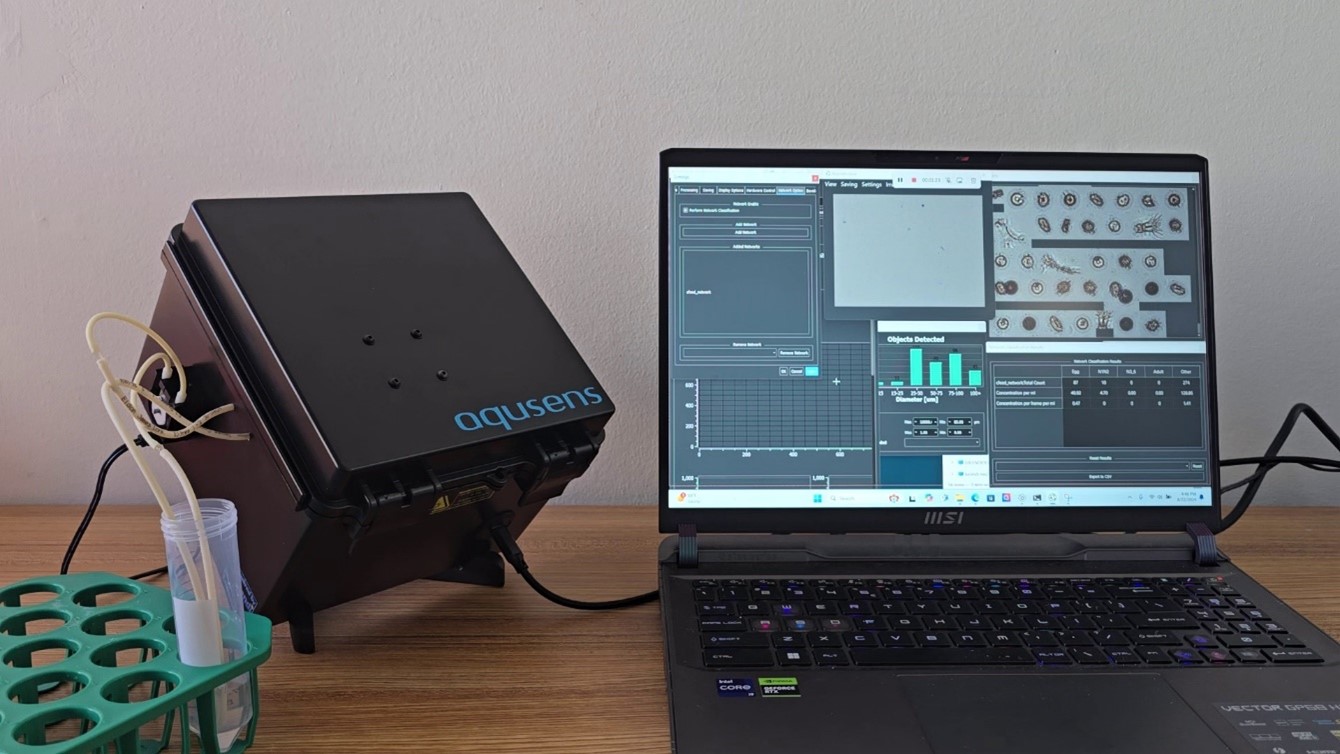 black box connected to test tube, plugged into laptop with charts and graphs on the screen