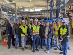 Group of people in hard hats standing in warehouse
