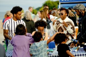 Children work on a water craft while adults talk behind them.