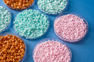 round plastic dishes filled with plastic pellets in blue, pink and orange sitting on blue background