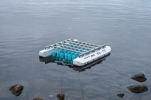 Floating system of metal bars across two white buoys with blue cylinders underneath.