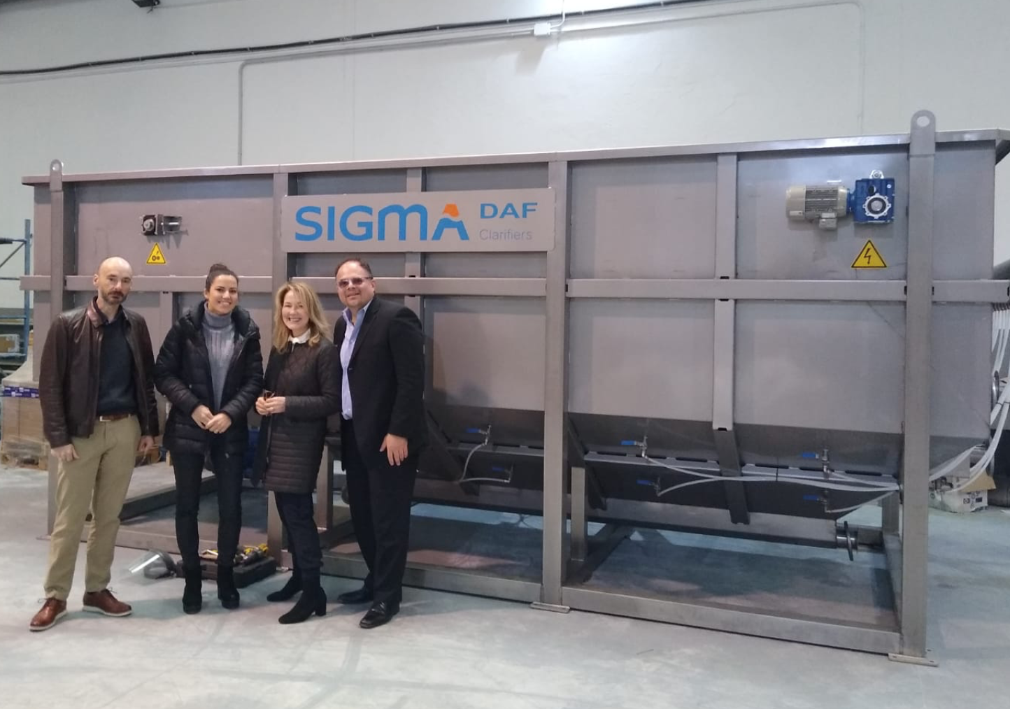 People stand under a SIGMA DAF sign.