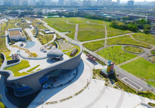 Industrial building with a green roof surrounded by green parkland.