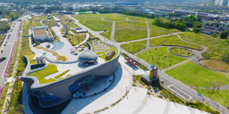Industrial building with a green roof surrounded by green parkland.