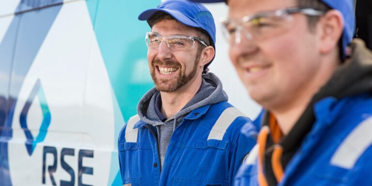 Two men in blue hats in front of van with RSE logo