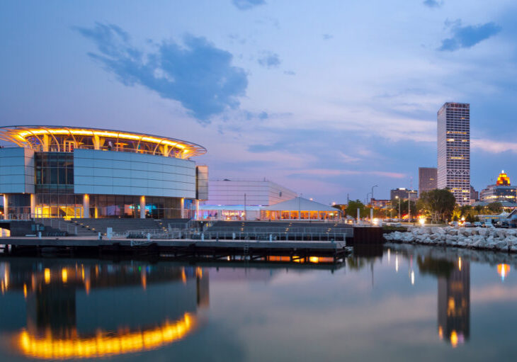 Image of Milwaukee skyline at twilight with city reflection in lake Michigan and harbor pier.